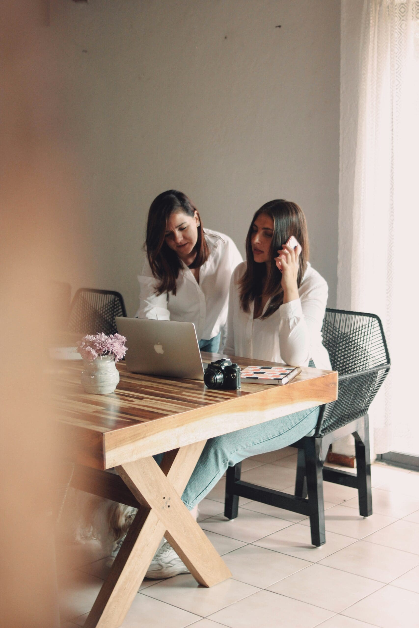 Two individuals appear to be collaborating on a laptop at a wooden table, suggesting the planning and design process behind an event professional's portfolio website aimed at booking more clients. #eventportfolio #websitedesign #clientbooking