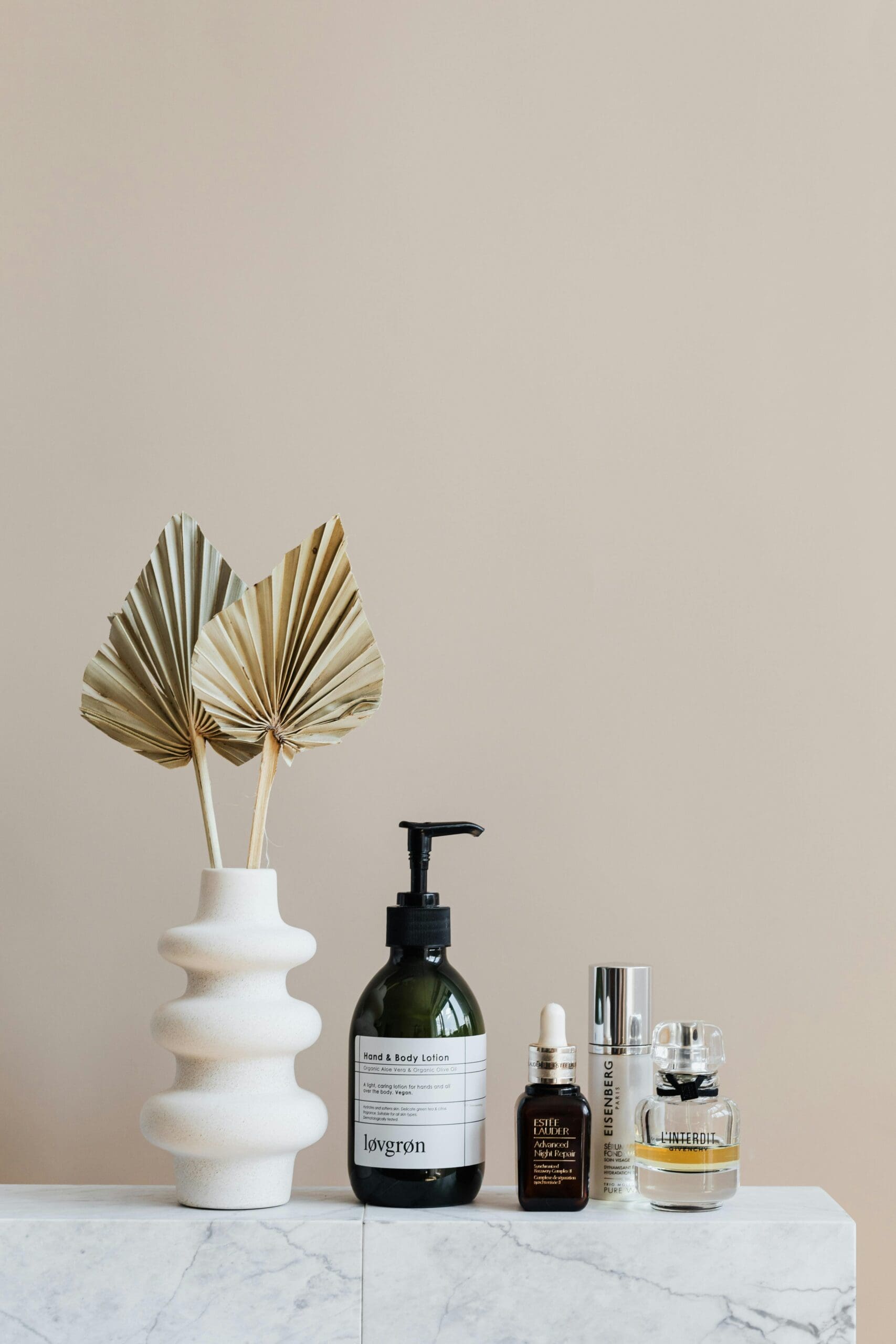 A thoughtfully arranged collection of beauty and skincare products alongside decorative dried palm leaves, showcasing how design can elevate the presentation of curated items. #curatedproducts #productdisplay #aestheticdesign